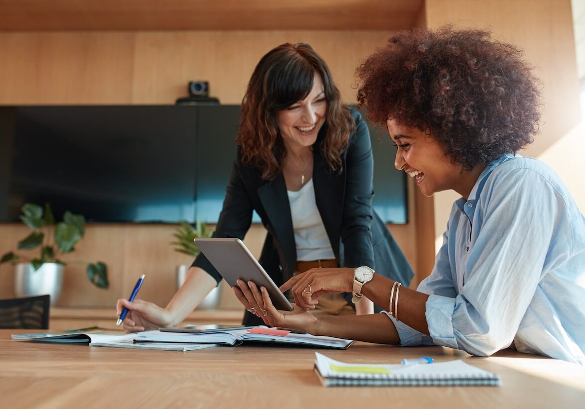 Shot of two young woman working together on digital tablet. Creative female executives meeting in a office using tablet pc and smiling.