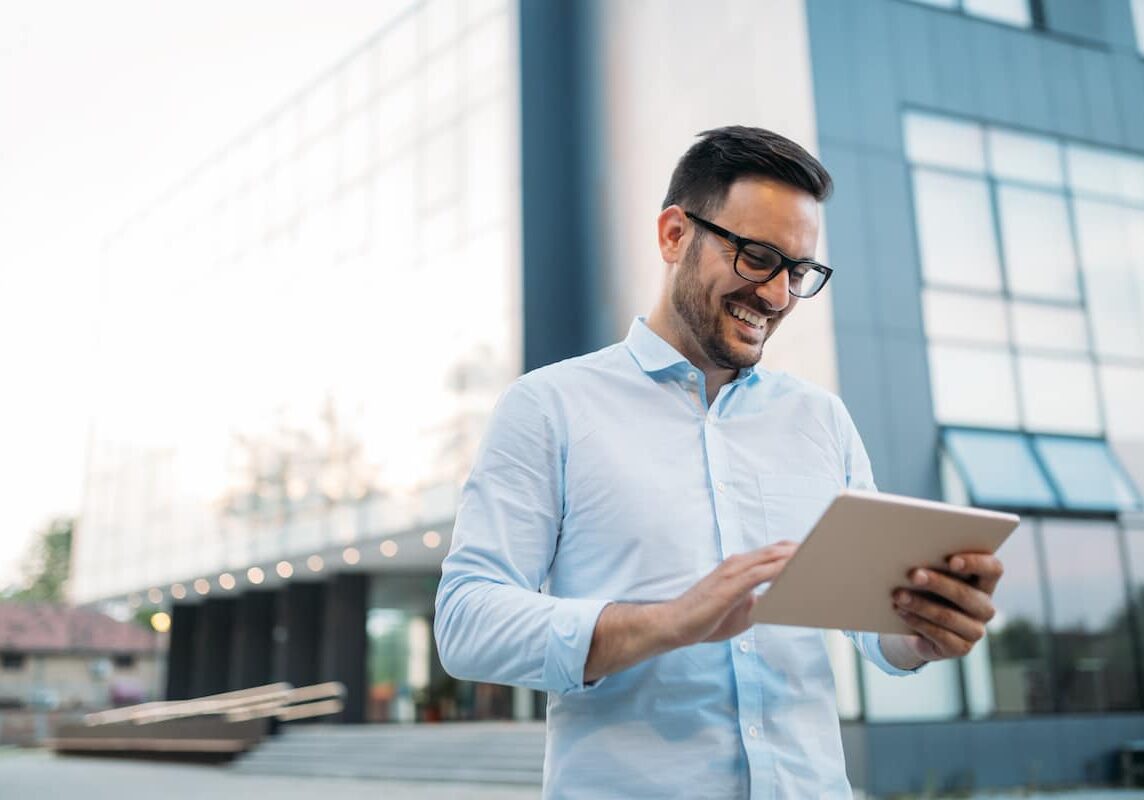 Portrait of businessman in glasses holding tablet outdoors