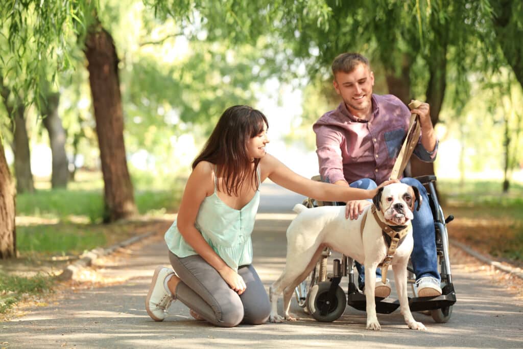Young man in wheelchair with his wife and service dog