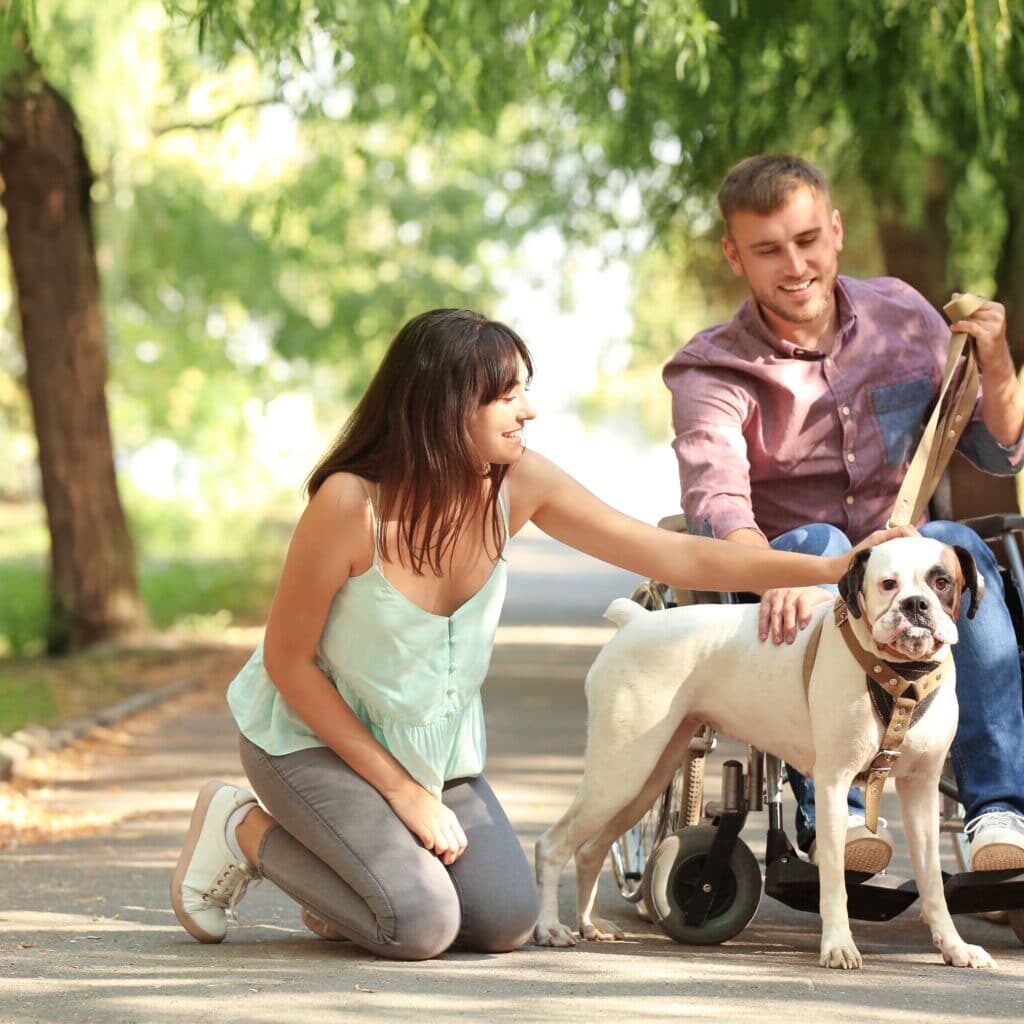 Young man in wheelchair with his wife and service dog