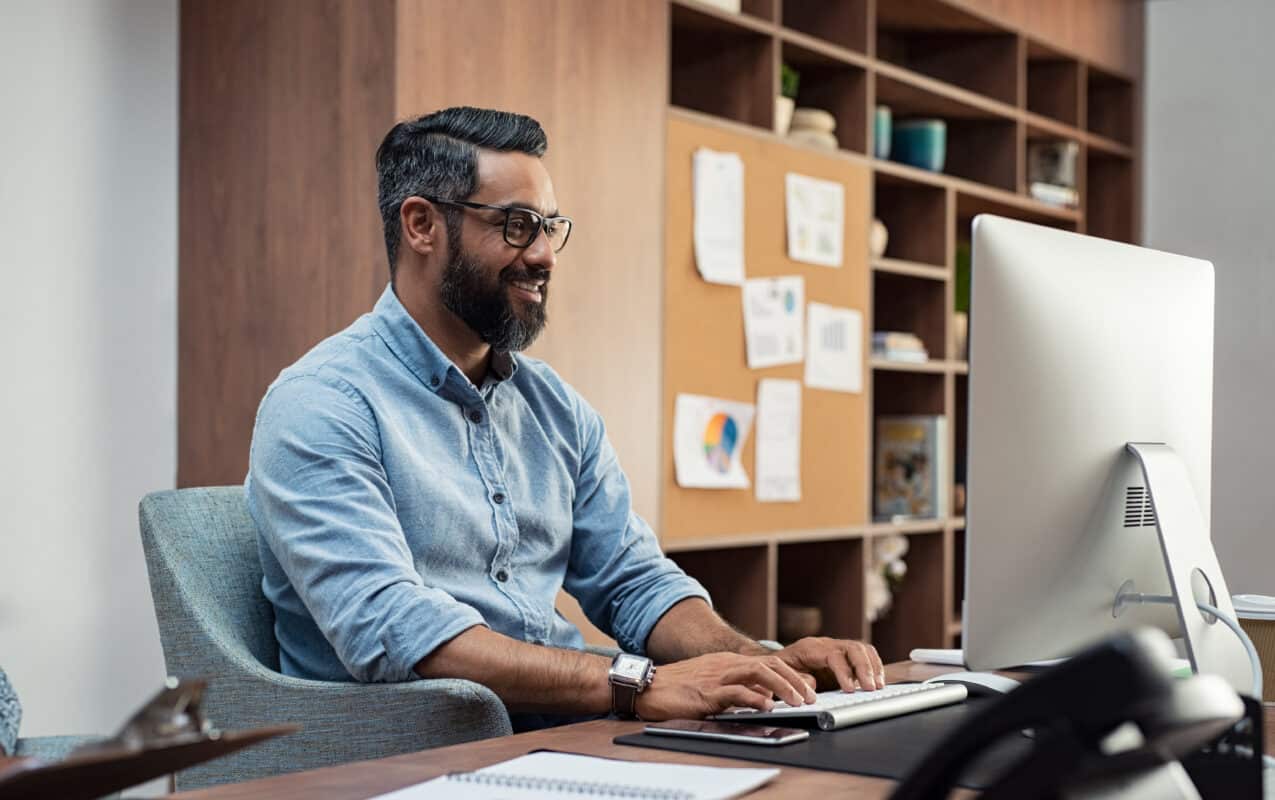 multifamily training director man, smiling and staring at computer screen