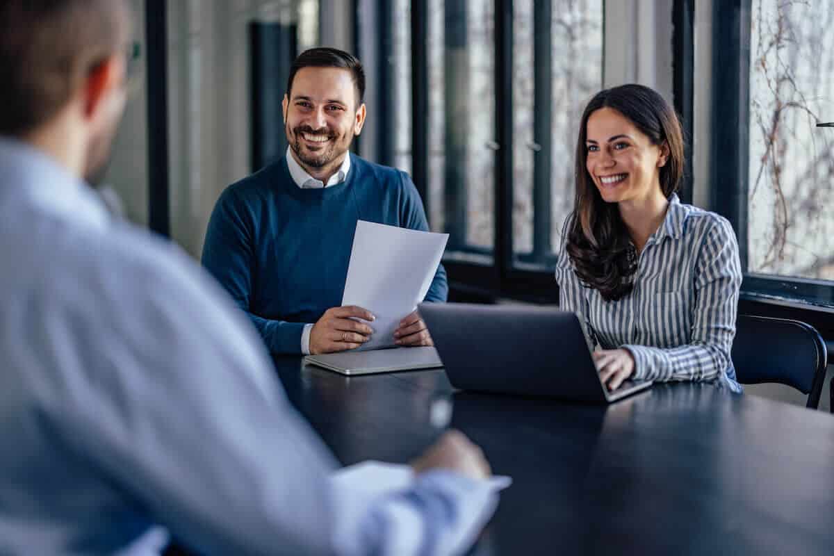 Happy couple sitting at desk with a laptop