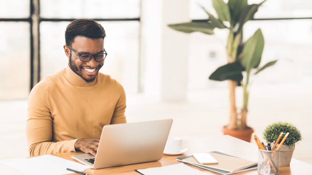 Headshot of handsome black guy using laptop, working in multifamily marketing