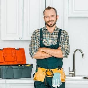 smiling handsome multifamily maintenance director with cross arms and looking at camera in resident's kitchen