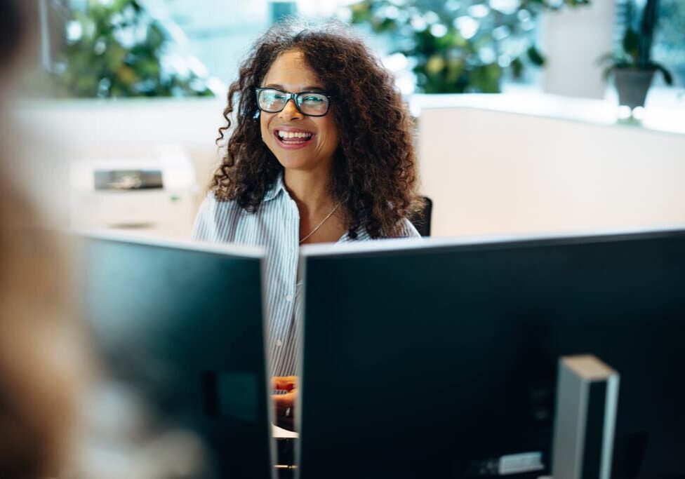 Smiling woman working at front desk of a commercial real estate office.
