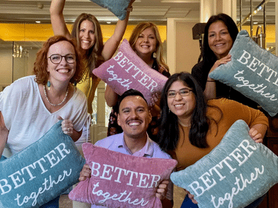 Grace Hill team members holding up pillows that read 